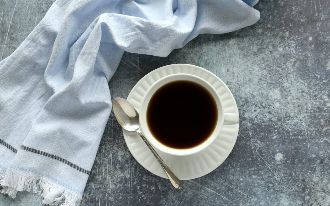 Flat lay of cup of coffee or tea in teacup on blue slate background with blue towel, background